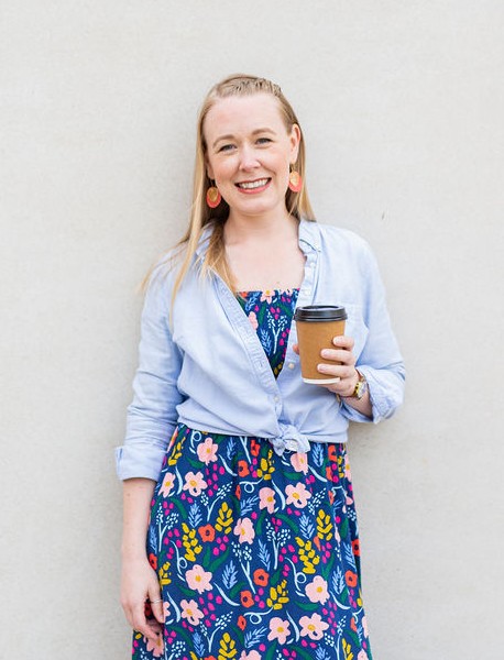 Lindsey Hall holding a coffee and smiling warmly in a colourful floral dress – friendly, down-to-earth coach helping parents through divorce and co-parenting.