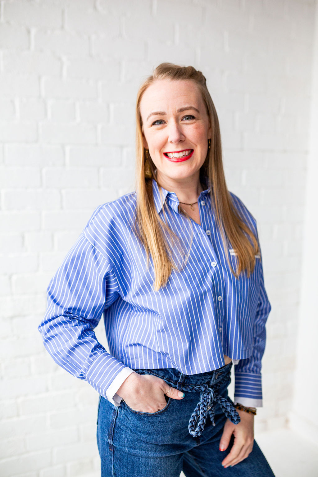 Lindsey Hall, Divorce and Intimacy Coach, smiling with hands in pockets against a white brick wall—grounded and confident as she shares her professional pivot from corporate accounting to deeply personal coaching work.