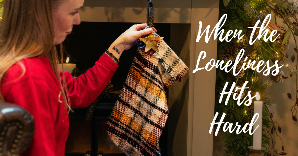 Woman looking sad as she hangs a single stocking by the fire